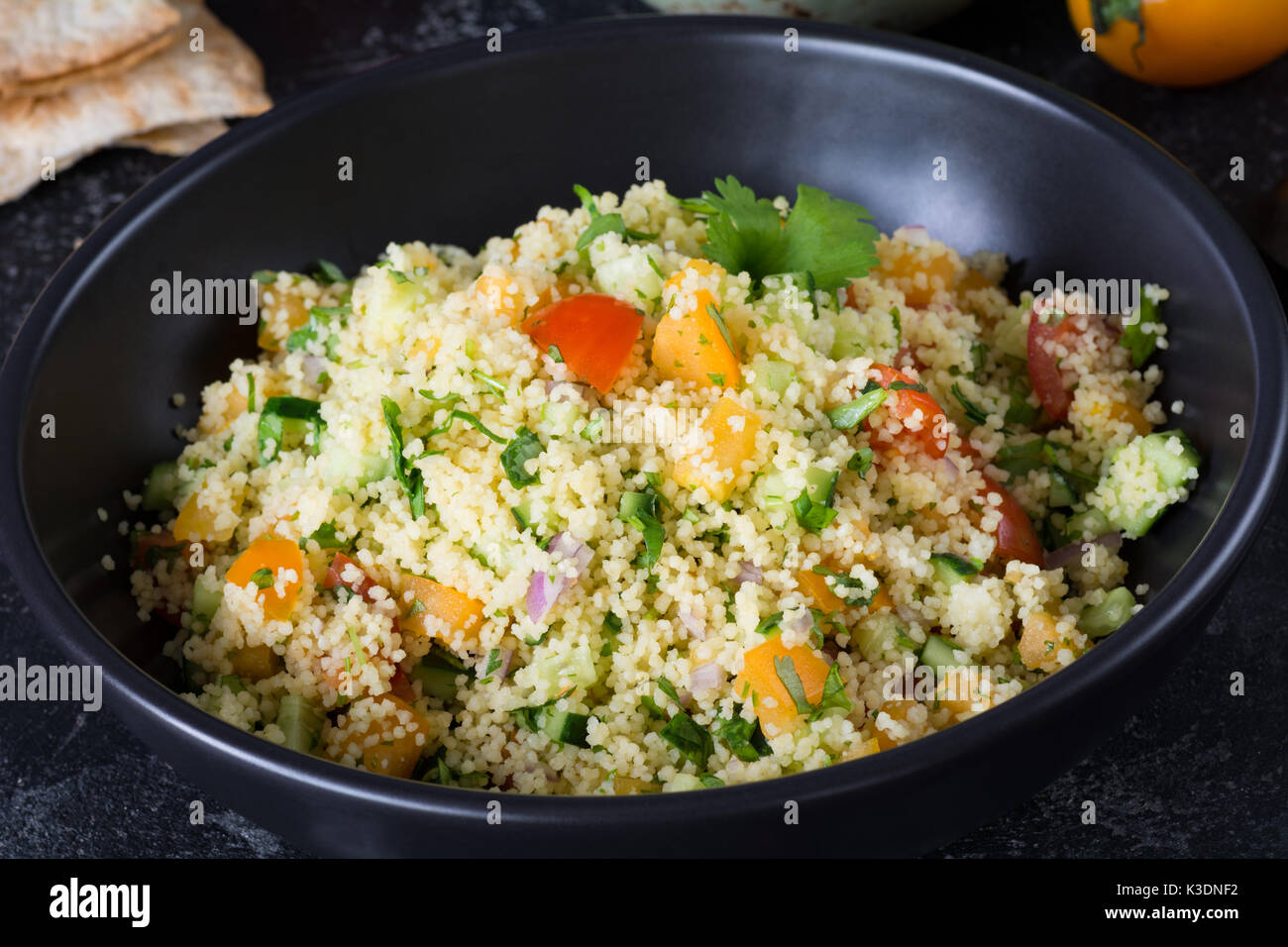 Lebanese arabic cuisine: healthy delicious salad with cous cous, fresh vegetables and greens called Tabbouleh in black bowl. Authentic food bowl Stock Photo