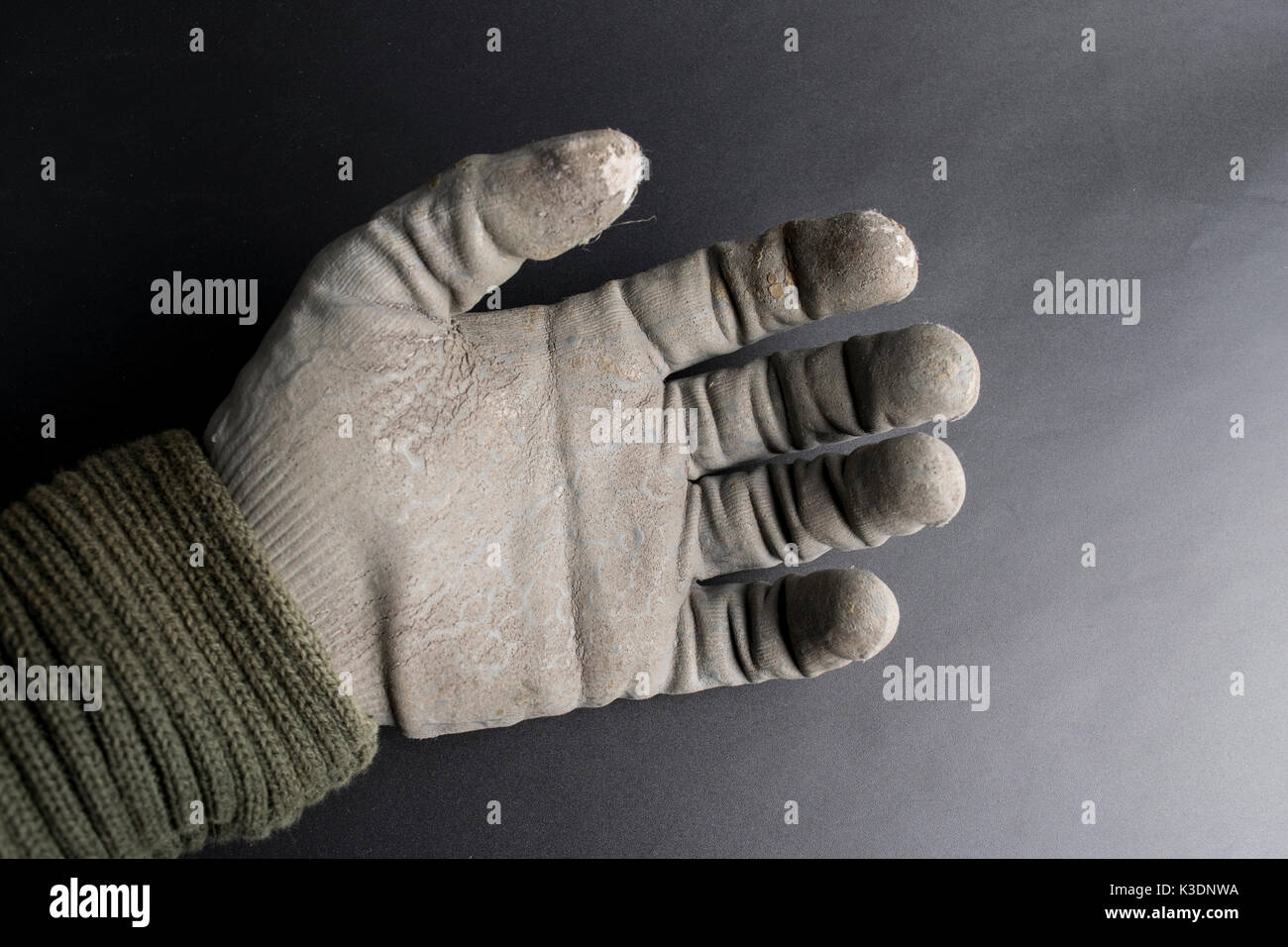 Isolated worn out working gloves against a black surface Stock