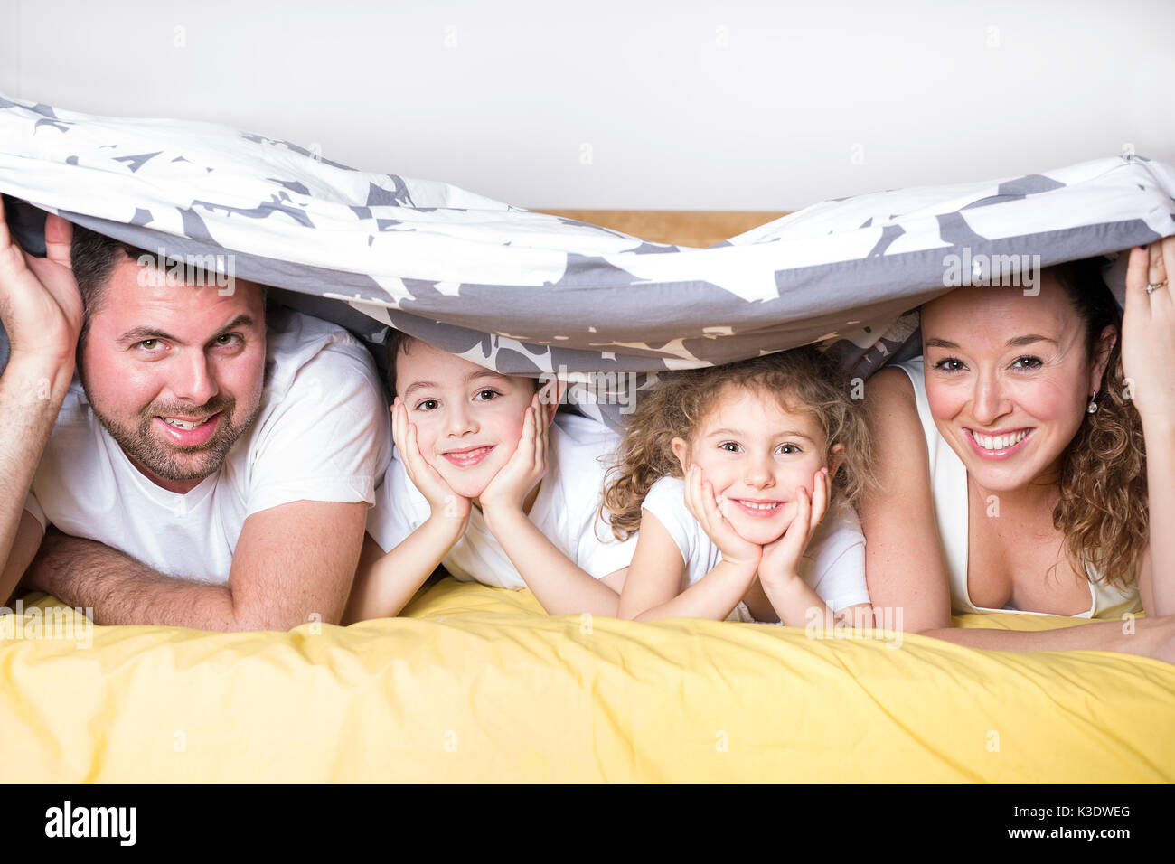 family, children and home concept - happy family with two kids under blanket at home Stock Photo