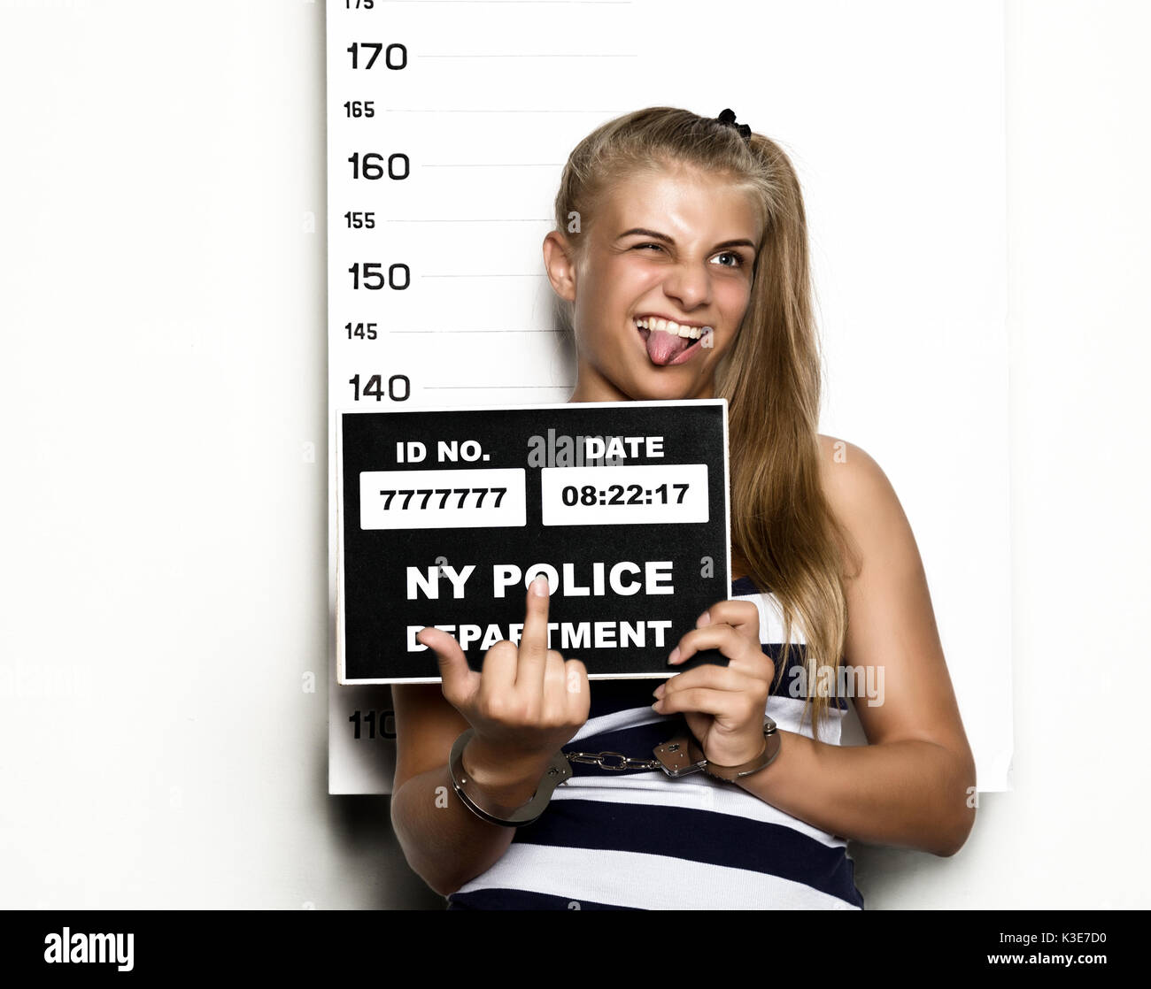 Young beautiful blonde woman Criminal Mug Shots. imprisoned girl shows middle finger Stock Photo