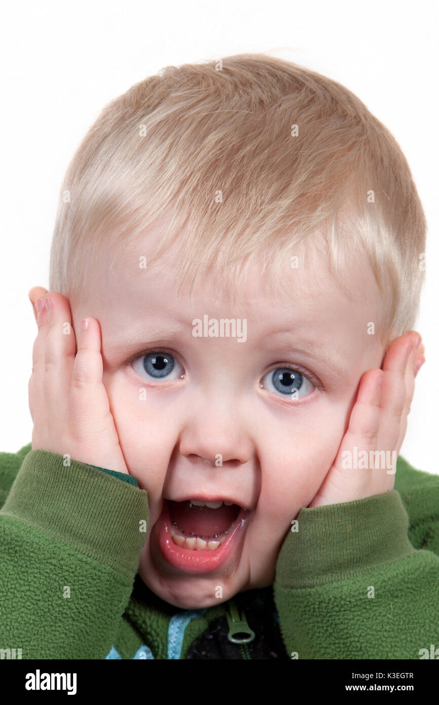 Cute young toddler screaming with his hands on his face. Stock Photo