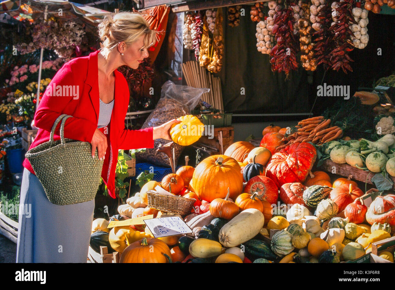 Young Woman while shopping at the town market looks at pumpkins Stock Photo