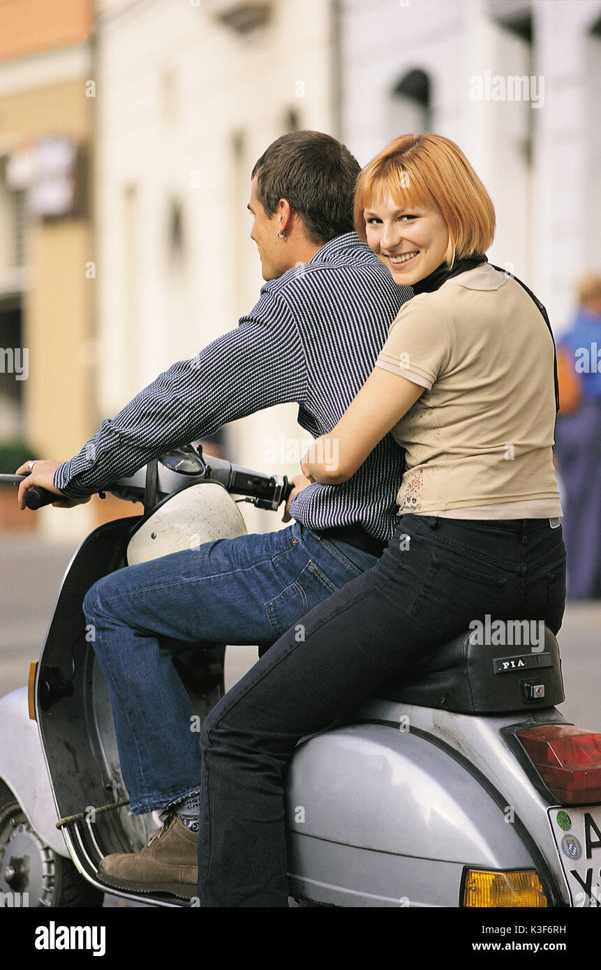 Youthful couple on Vespa motor scooter. Woman looks over the shoulder Stock Photo