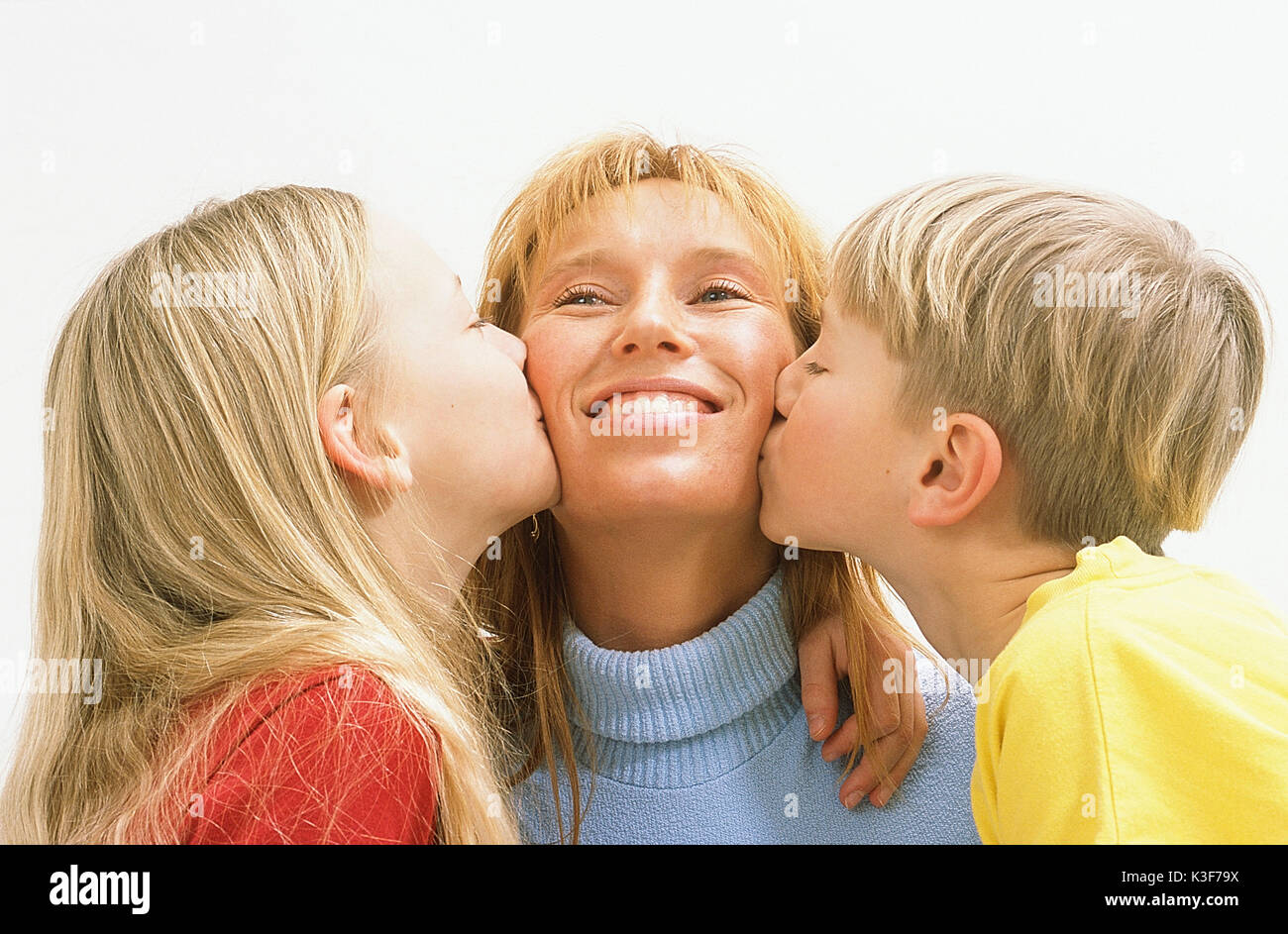 daughter and son kiss mother on the cheeks Stock Photo