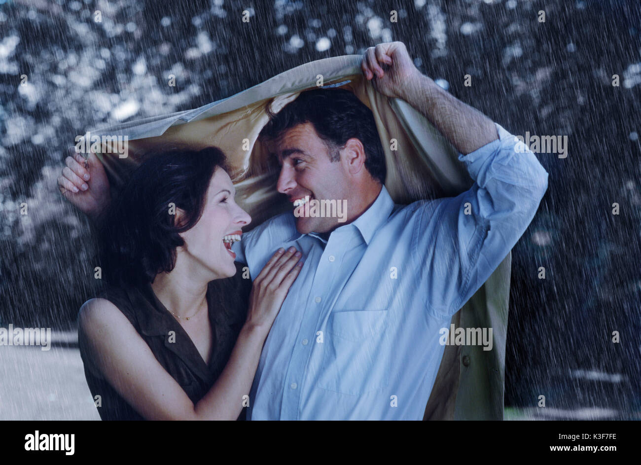 Couple protects himself with a jacket from rains Stock Photo