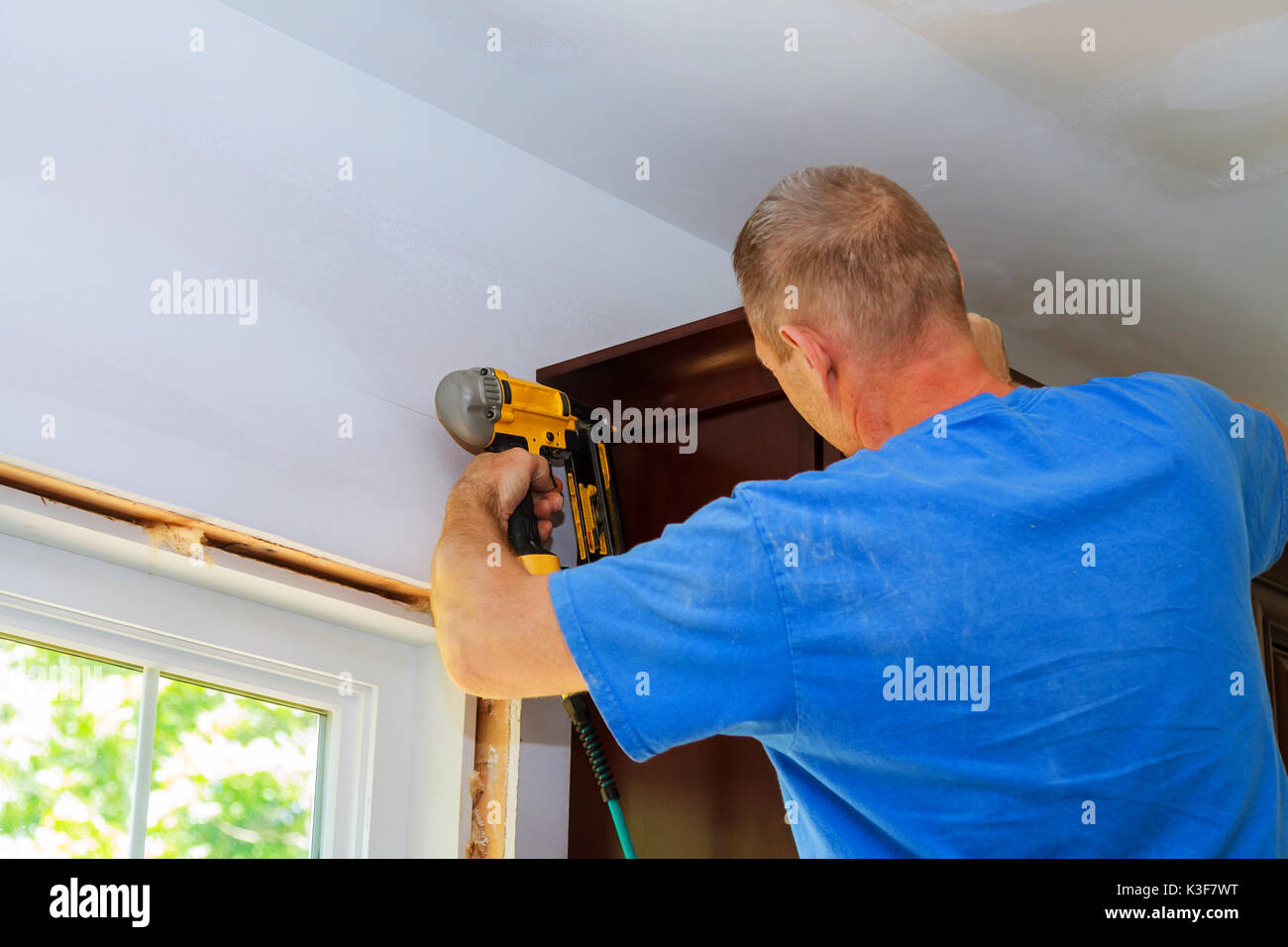 Carpenter brad using nail gun to Crown Moulding on kitchen