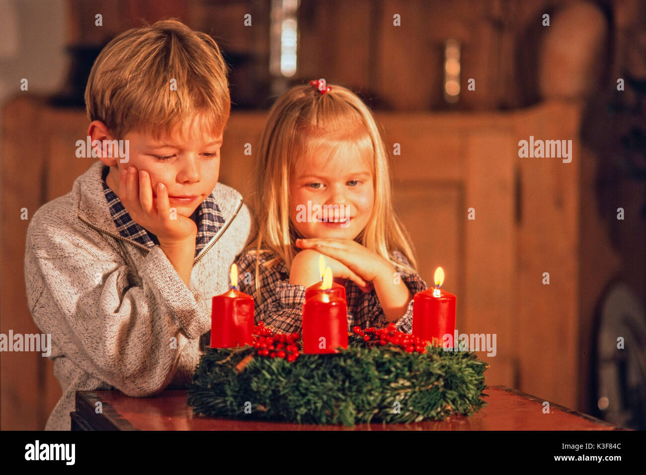 Two children while an Advent wreath where all four candles burn Stock Photo