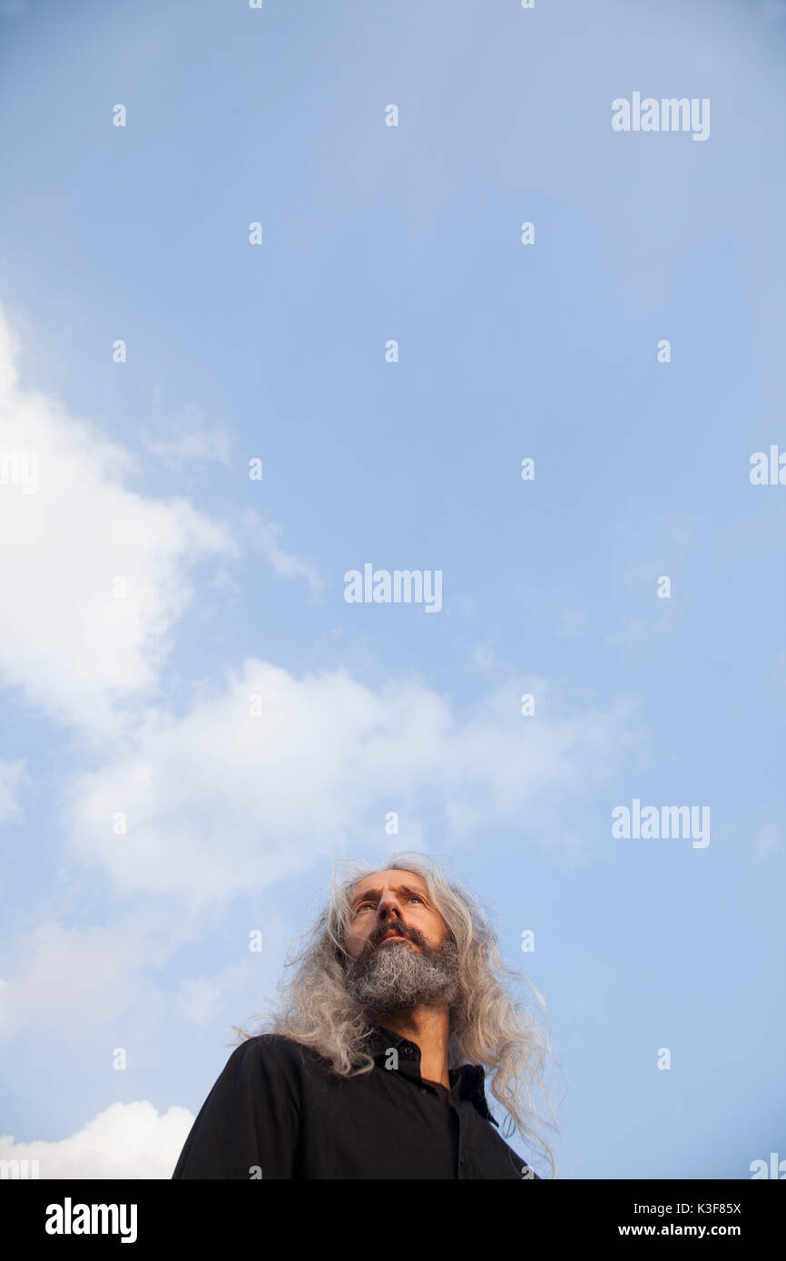 Low Angle View Portrait of Contemplative Mid-Adult Man with Beard and Long Hair Stock Photo