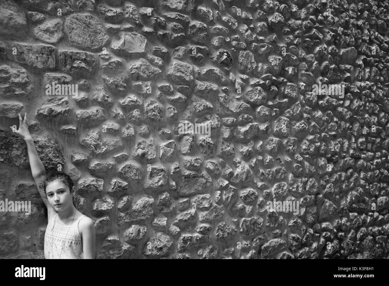 Portrait of Teen Girl with Raised Arm against Stone Wall Stock Photo
