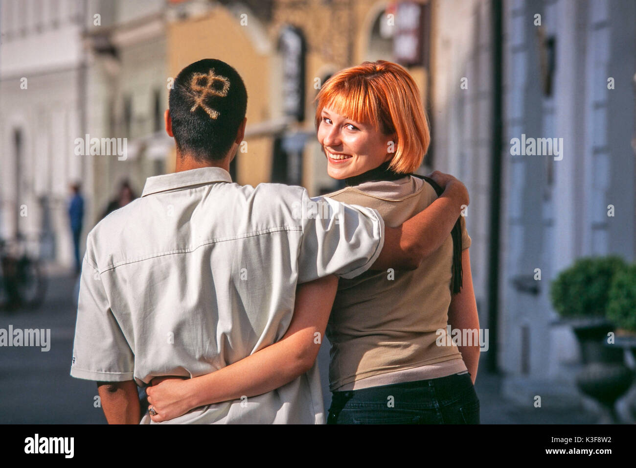 Couple from the back. Woman turns round and looks over the shoulder. Stock Photo