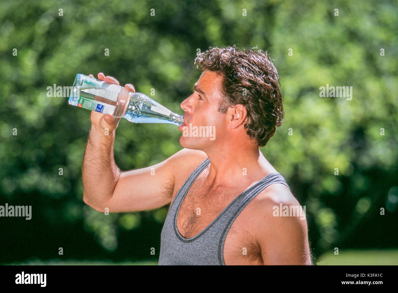 Man at the sports outfit drinks water from bottle Stock Photo