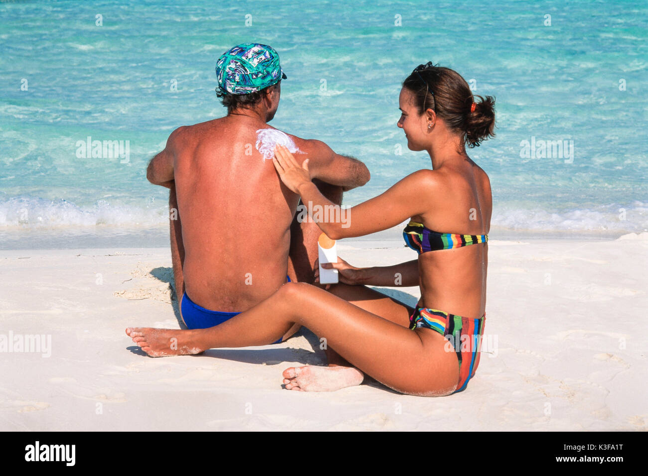 Woman creams man the back with sun lotion Stock Photo