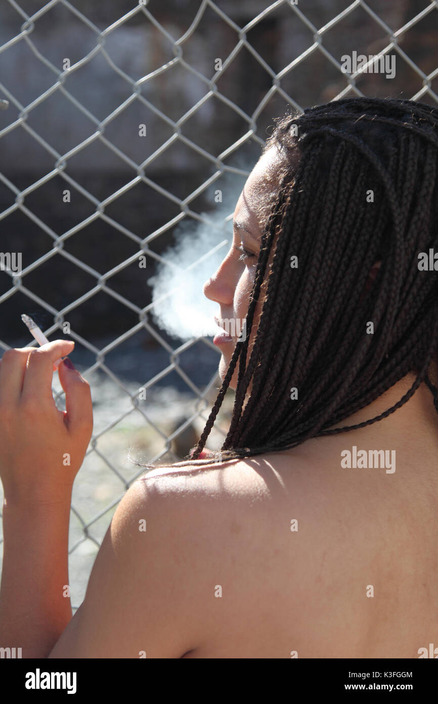 black woman metal fence smoking Stock Photo