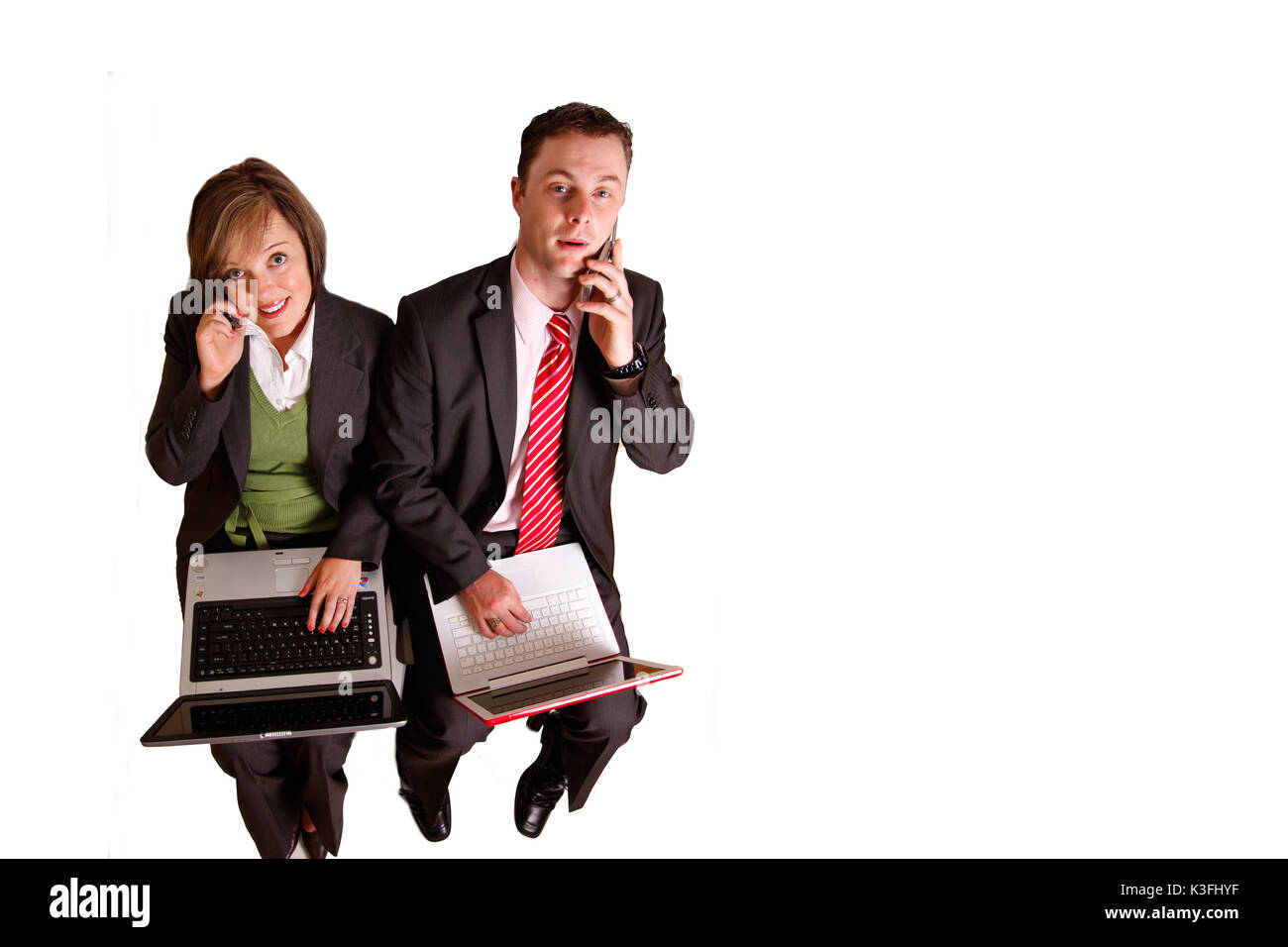 a business man and woman sit working on laptops and cellphones Stock Photo