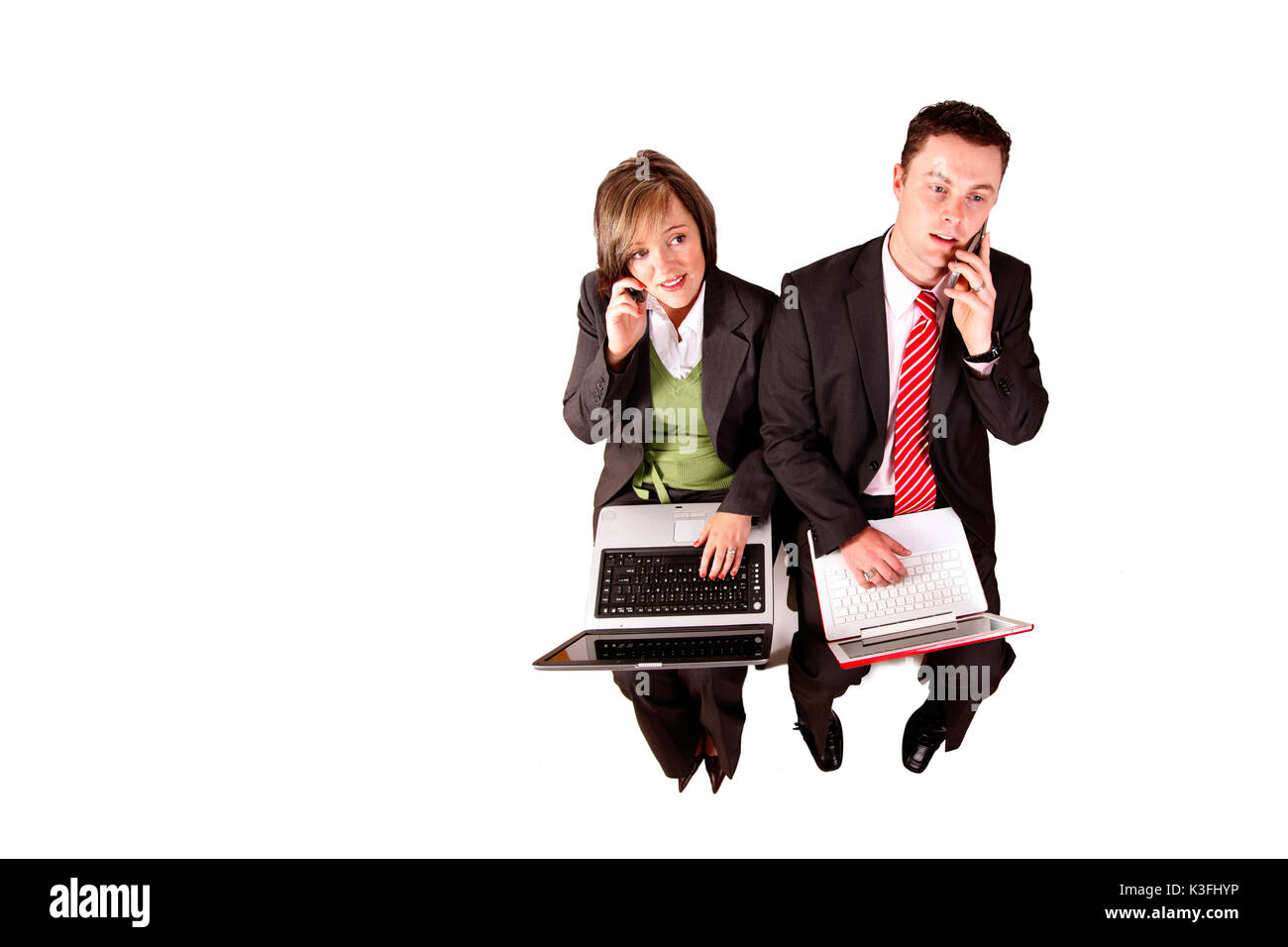 a man and woman in a white studio collaborate with latops and cellphones, communicating about finance, accounting or business Stock Photo