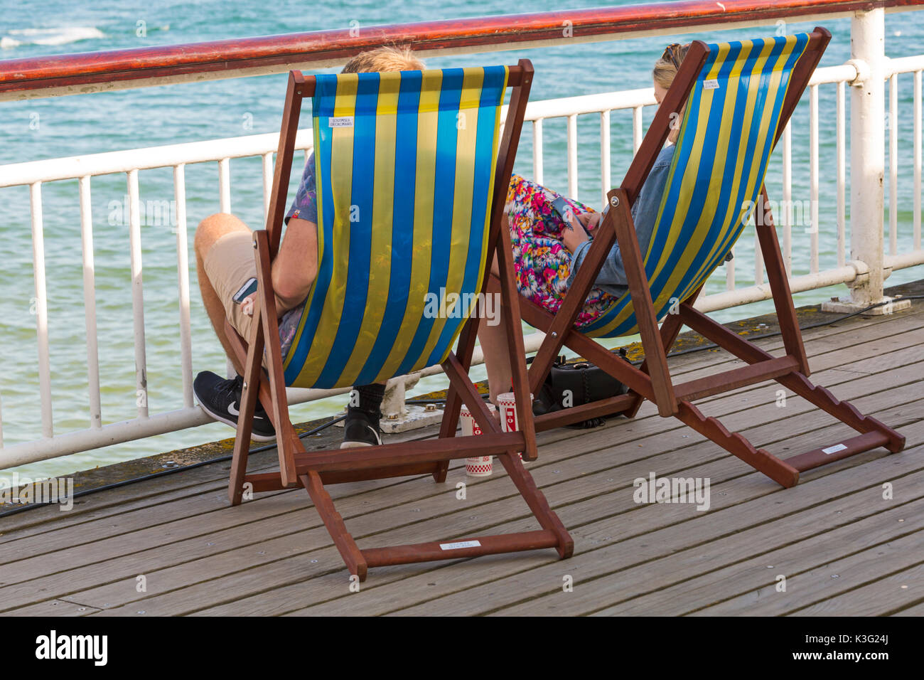 Bournemouth, Dorset, UK. 2nd Sept, 2017. UK weather: lovely warm sunny day at Bournemouth beach. Couple relaxing in deckchairs on Bournemouth Pier - back view, rear view. Credit: Carolyn Jenkins/Alamy Live News Stock Photo
