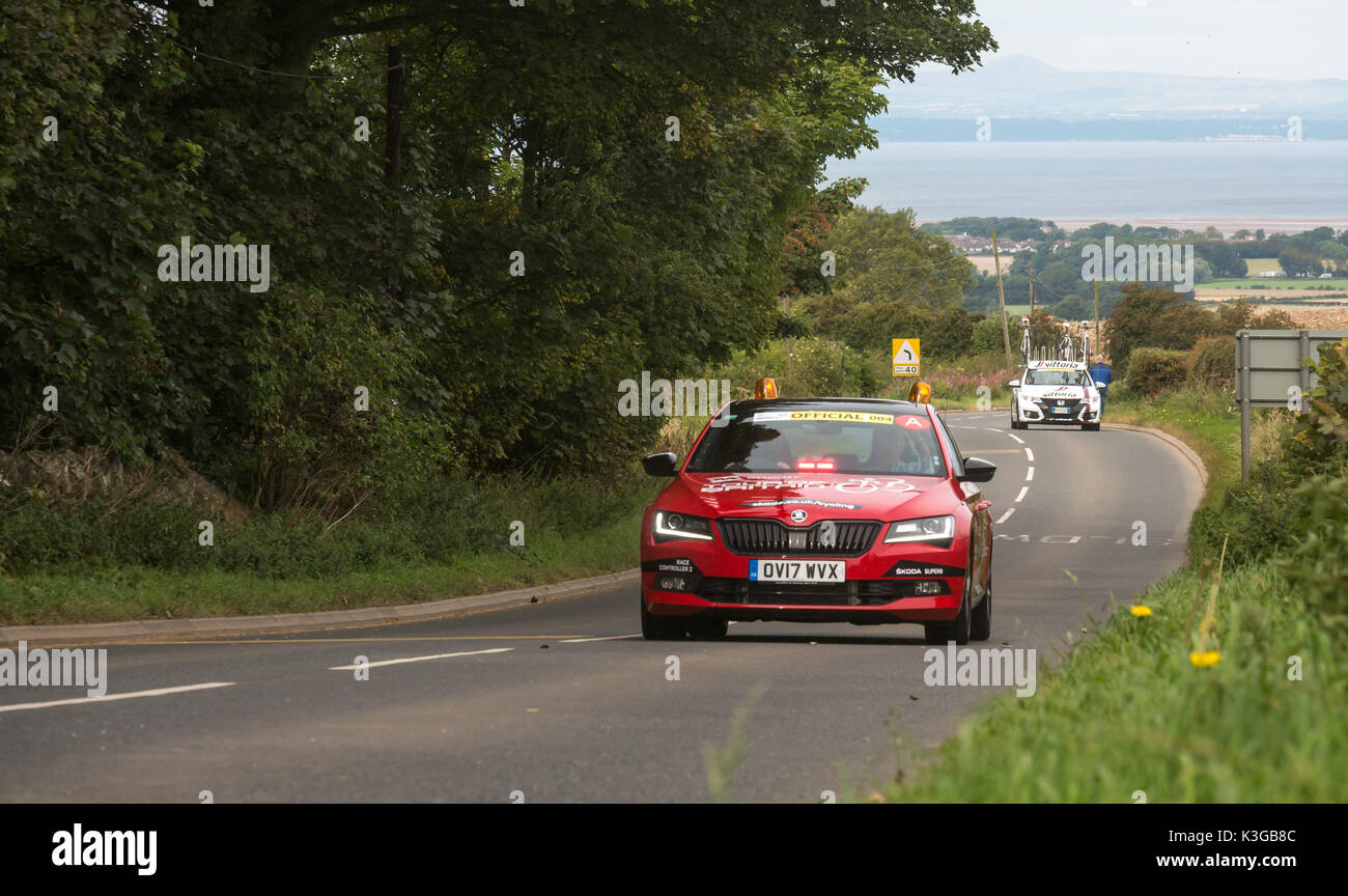 East Lothian, Scotland, United Kingdom, 3rd September 2017. Lead official cars in front of the main body of cyclists in the Tour of Britain Stage 1 cycling race as it passes over Byres Hill Stock Photo