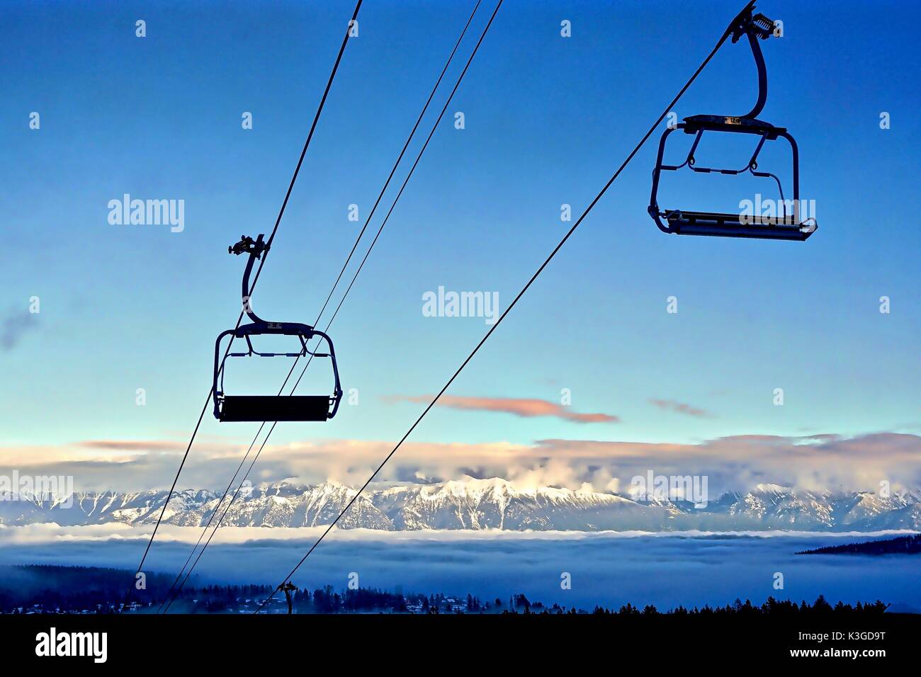 Empty ski lift chairs with snowy mountain background Stock Photo