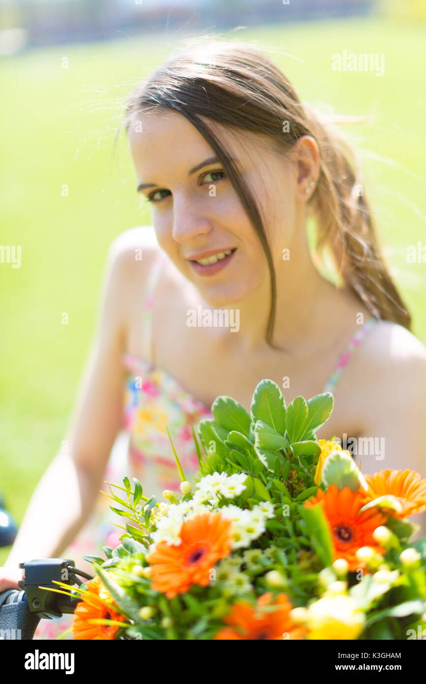 Portrait of a cute young woman with a bouquet of flowers in a summer ...