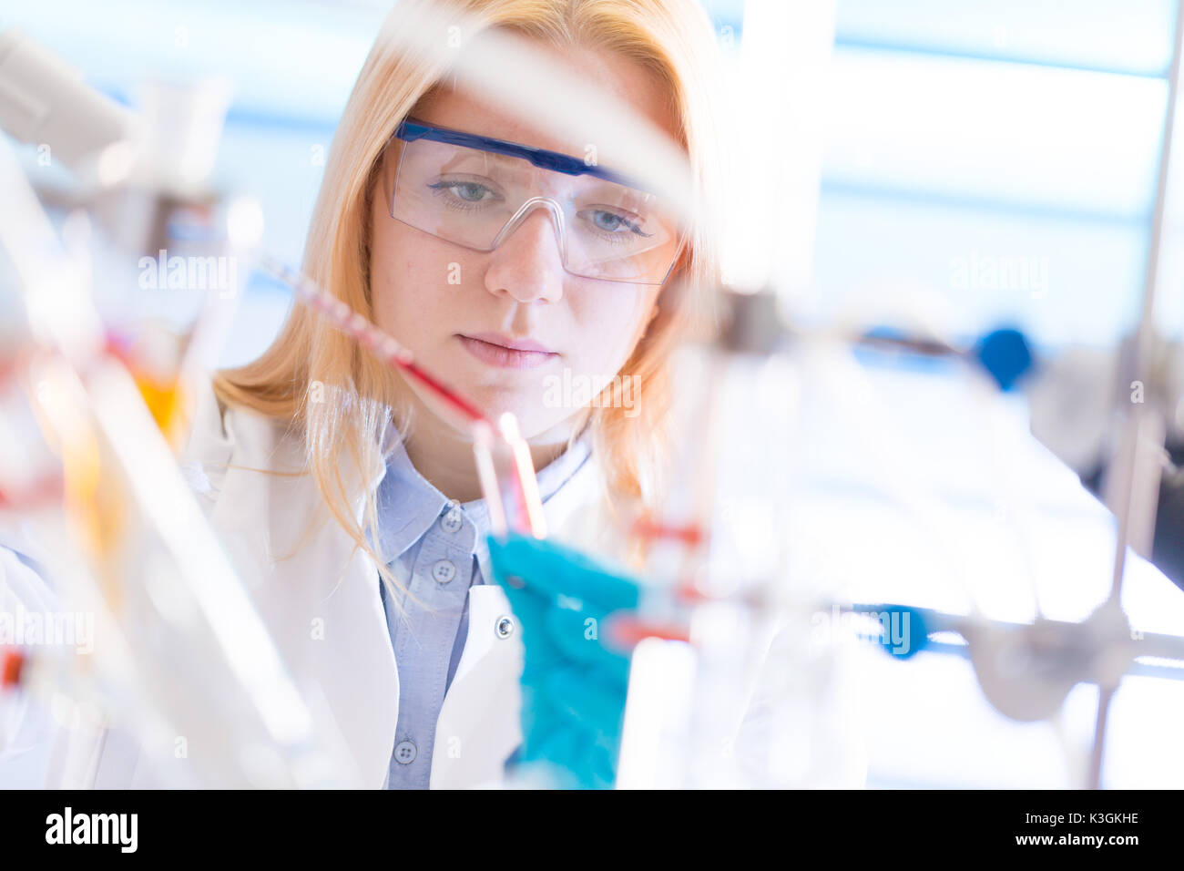 Female laboratory assistant with chemical experiment in scientific