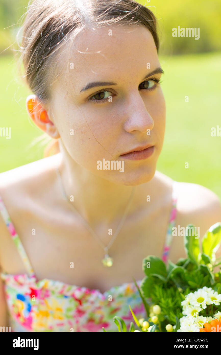 Portrait of a cute young woman with a bouquet of flowers in a summer ...