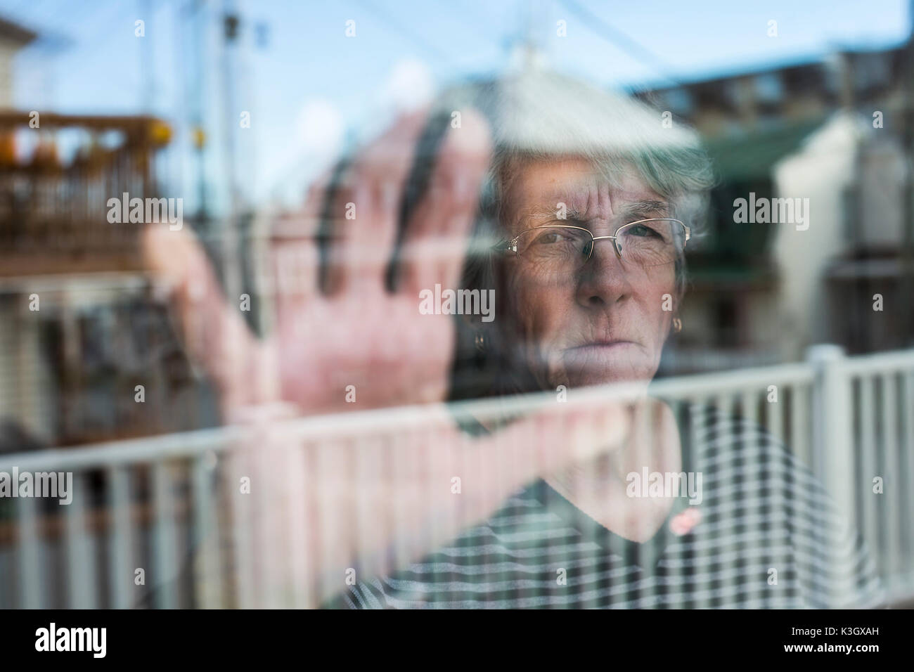 Senior woman looking out through a window like depress Stock Photo