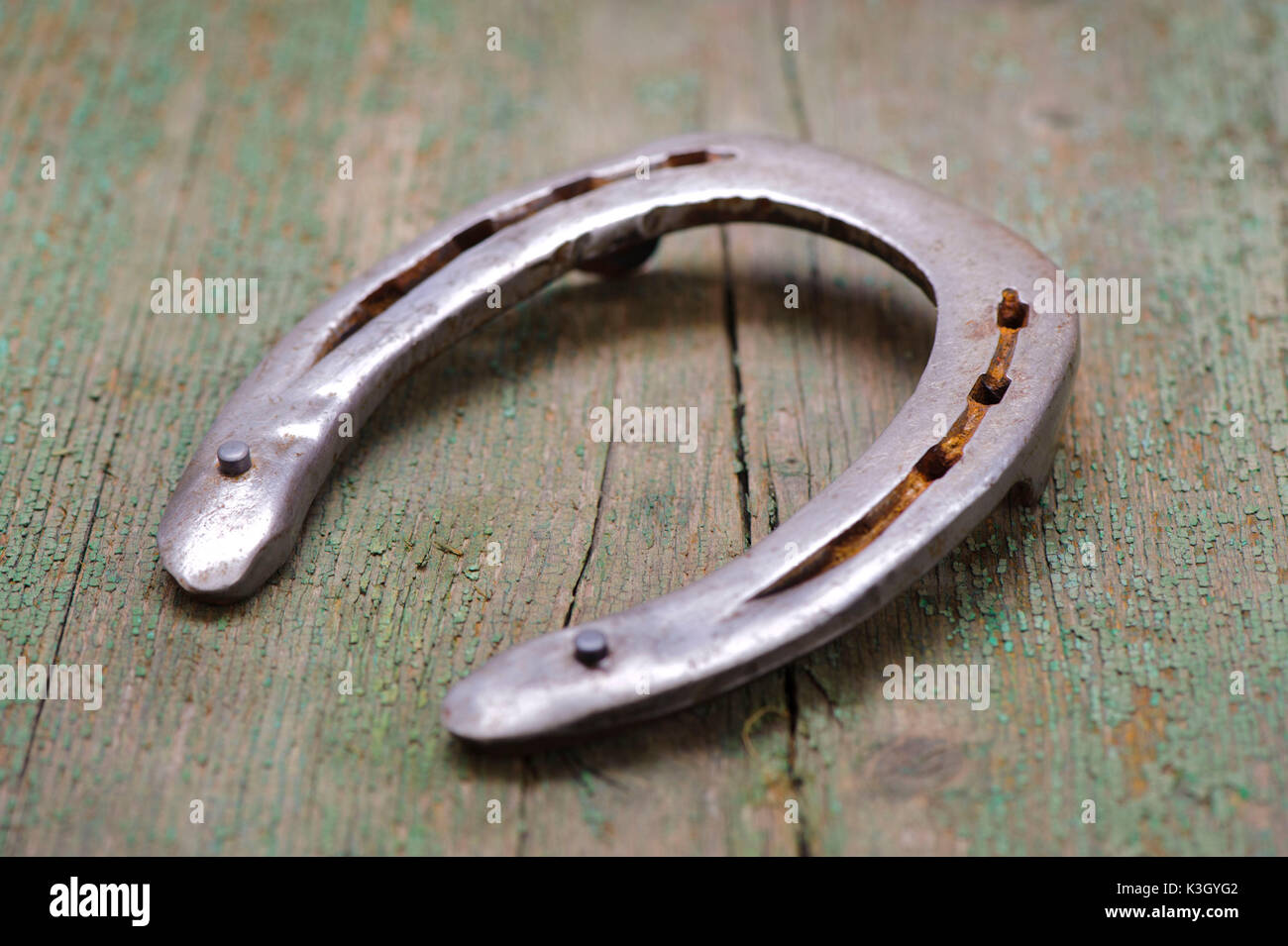 Horseshoe as a lucky charm lies on old wooden board Stock Photo