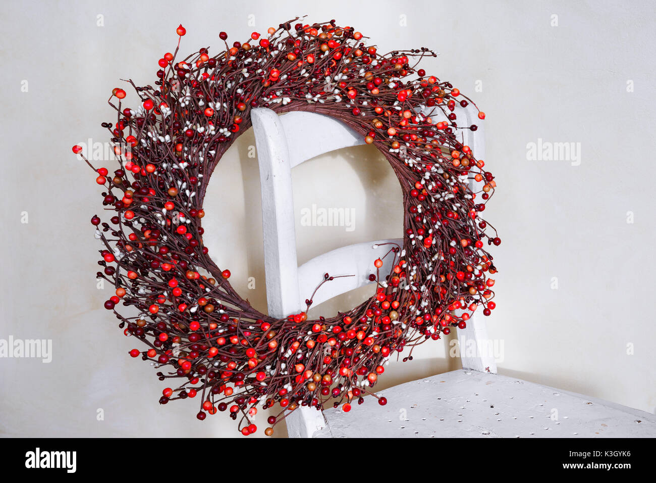 Red berry Christmas wreath hnging on the back of an old chair. Stock Photo