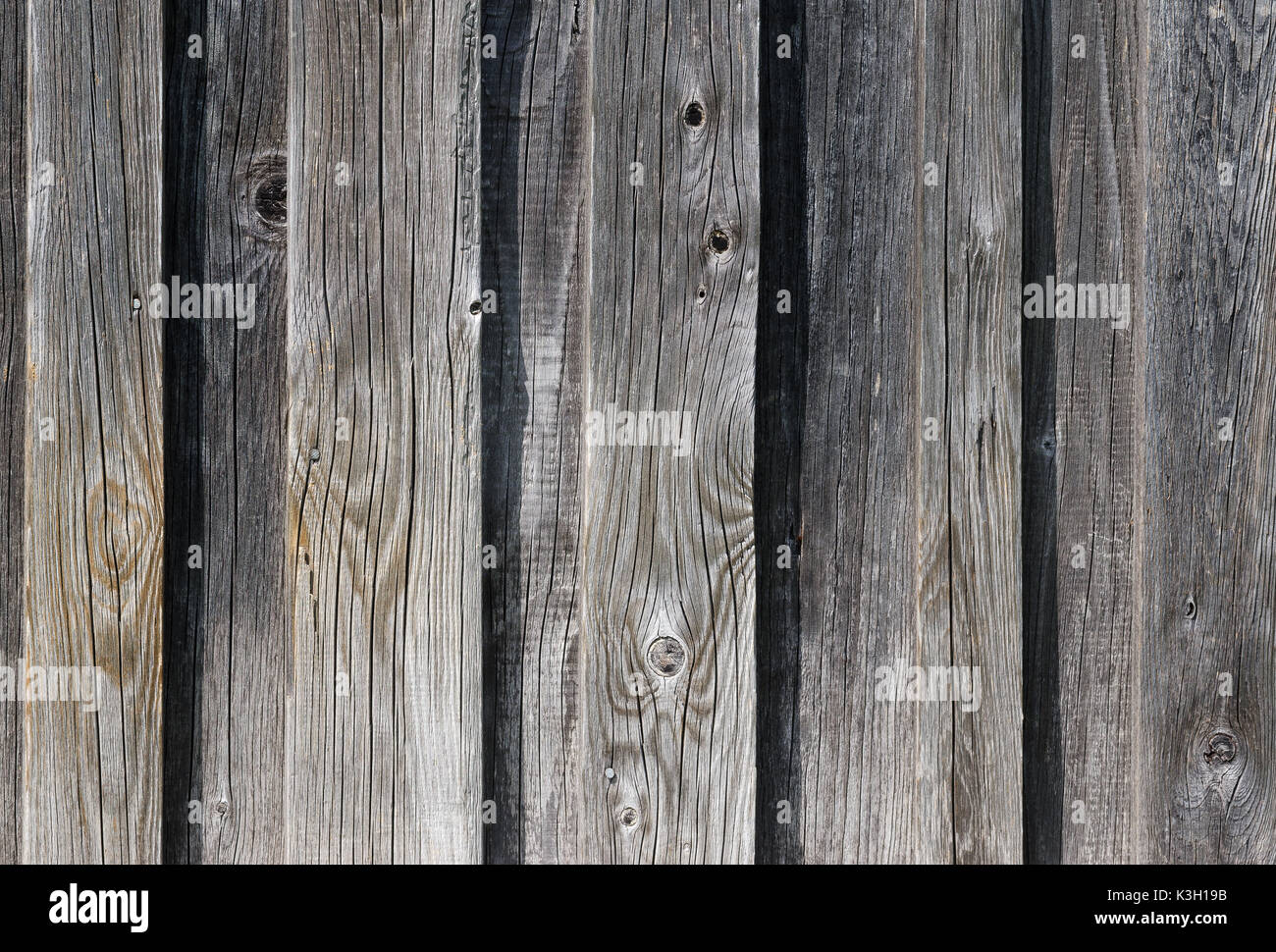 Weathered old wooden wall detail. Simple gray boards with knotholes and coarse grain nailed together. Outdoor. Backgrounds. Photo. Stock Photo