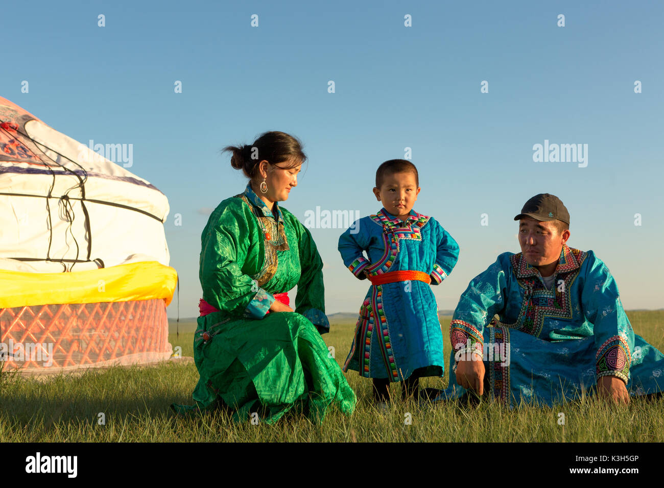 Inner Mongolia, China-July 30, 2017: Nomadic Mongolian family with their traditional colorful dresses near their yurt in immense grassland of the coun Stock Photo