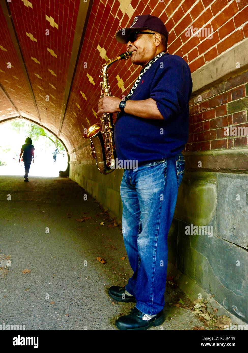 Saxophone player in cool shadows of Greywacke Arch, Central Park