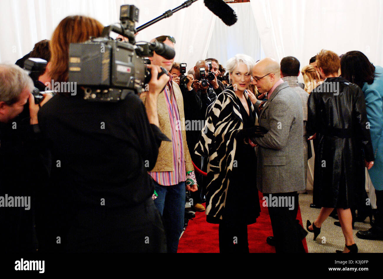 Miranda Priestly and fashion director Nigel (Stanley Tucci) arrive at a Paris fashion show. Miranda wears a boiled wool off white and black zebra print wrap coat by Charles Chang-Lima; and black wool jersey wrap dress with circle skirt by Donna Karan with wide brown leather belt by Valentino. PHOTOGRAPHS TO BE USED SOLELY FOR ADVERTISING, PROMOTION, PUBLICITY OR REVIEWS OF THIS SPECIFIC MOTION PICTURE AND TO REM     Date: 2006 Stock Photo