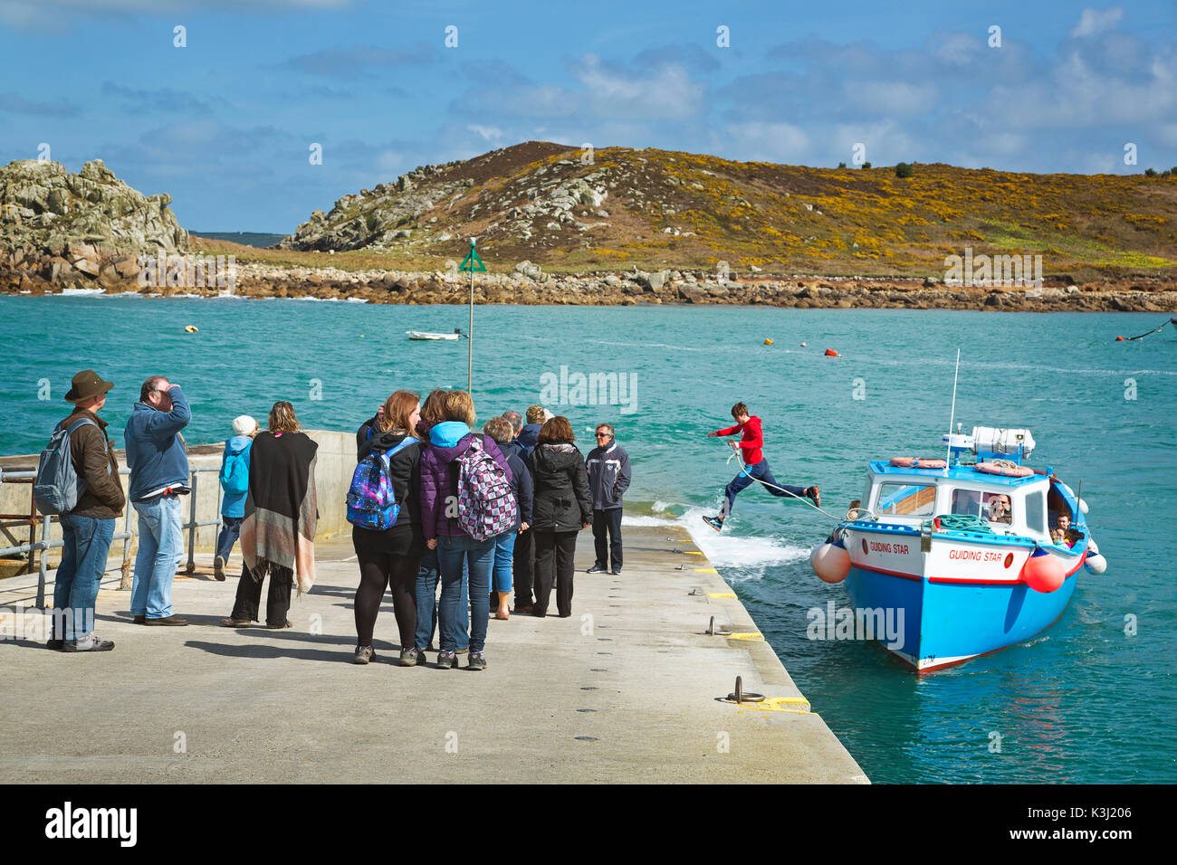 A young boatman leaps across to the quay in the Isles of Scilly, Cornwall, UK Stock Photo