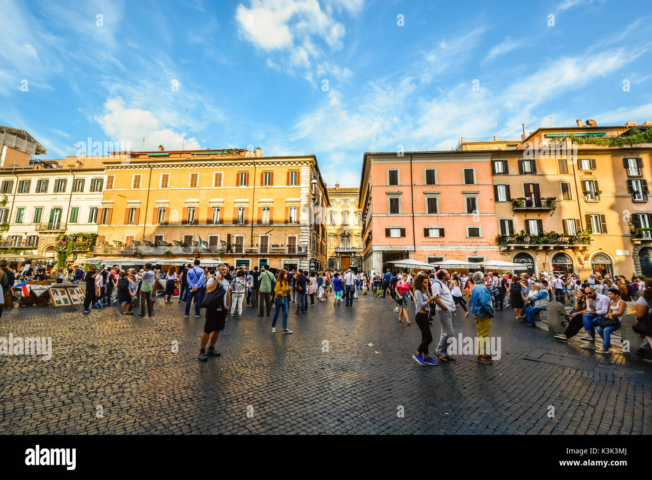 Later afternoon on the Piazza Navona as the sunlight shines off a window and locals and tourists enjoy themselves Stock Photo