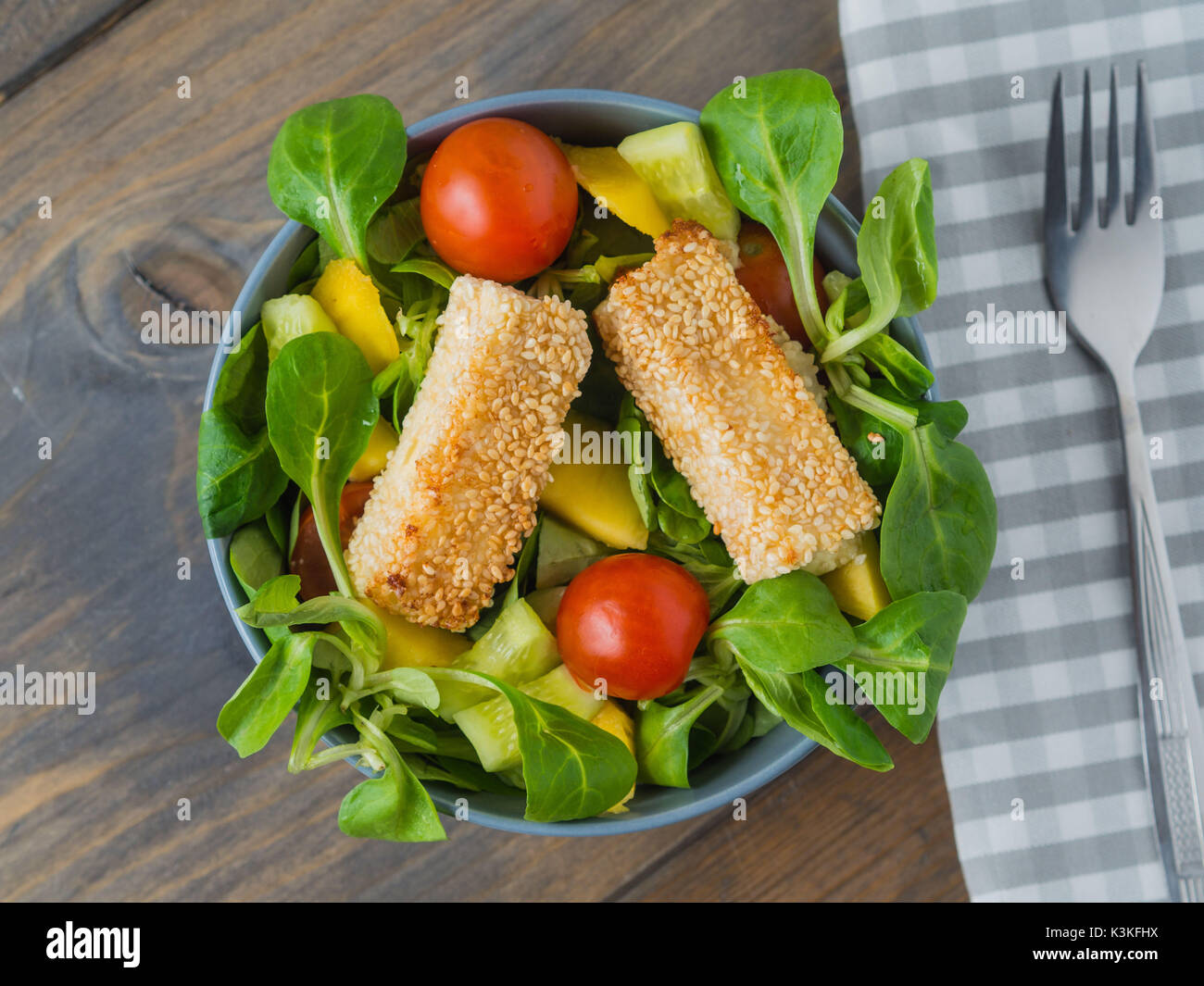 Baked feta cheese in sesame crust on mixed salad with mango Stock Photo