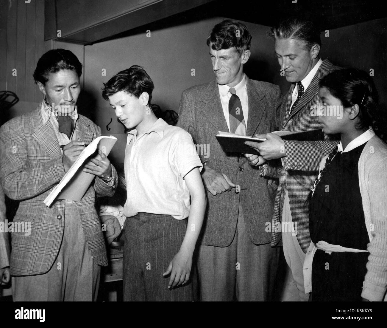 The climbers who conquered Mount Everest visit Beaconsfield Film Studios. SHERPA TENSING whose daughter NIMA looks on , signs a script for young actor JEREMY SPENSER watched by fellow mountaineer SIR EDMUND HILLARY while actor JOHN McCALLUM waits to get his script signed also. Stock Photo