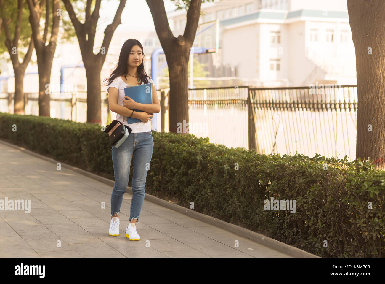 Girl carrying bag Walks in Campus Park Stock Photo