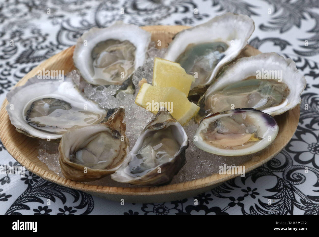 Oysters and a littleneck clam in an iced bowl with lemon Stock Photo