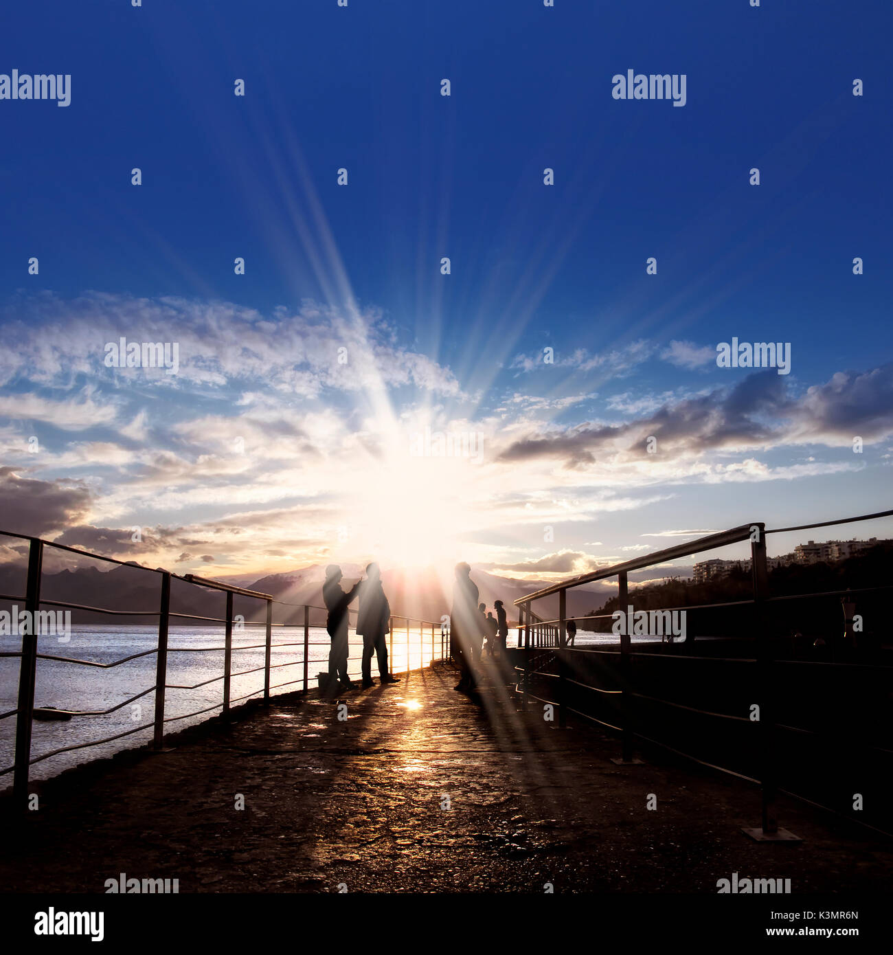 silhouetted people walking on street over sunset sky with sunbeam Stock ...