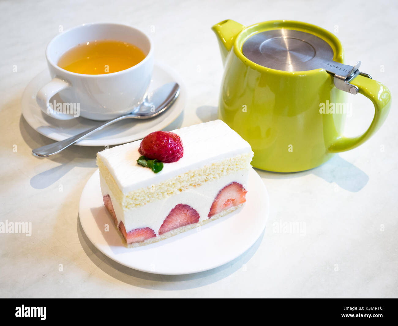 A slice of delicious strawberry shortcake, a popular dessert, and a cup of ginger tea. Stock Photo
