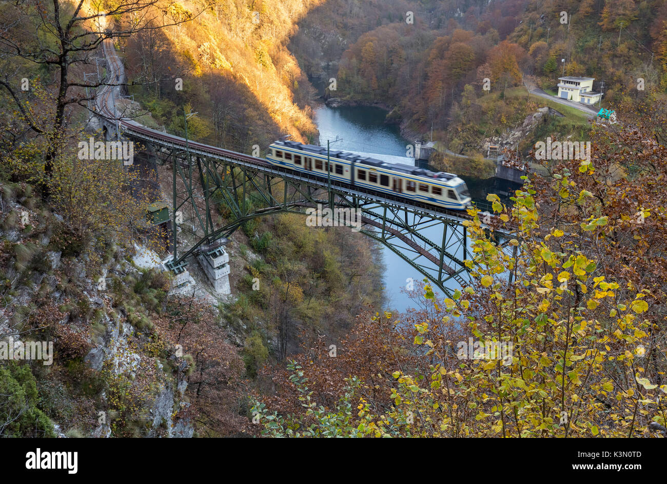 Vigezzina train passes over a steel bridge near Borgnone at sunset, Canton Ticino, Switzerland. Stock Photo