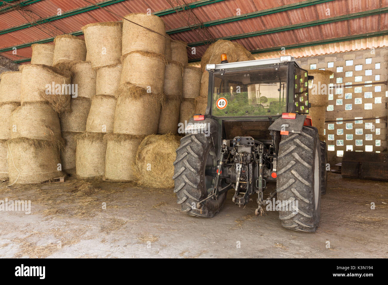 Tractors, equipment and bales of hay in the shed in front of the stables of Case Salet, State Natural Reserves, Monti del Sole Stock Photo