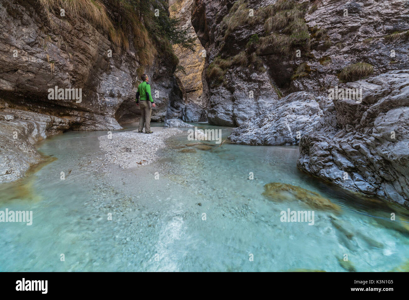 Dolomites, Belluno, Veneto, Italy. An hiker looking the turquoise water in Val Soffia, Mis valley Stock Photo