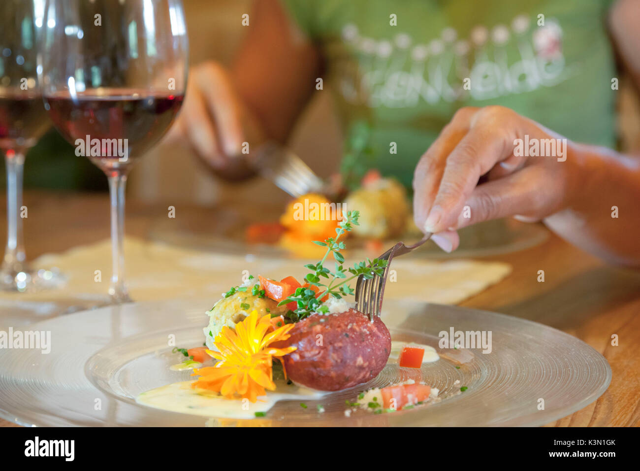the typical dumplings from South Tyrol in a beautiful plating and with two glasses of wine Stock Photo