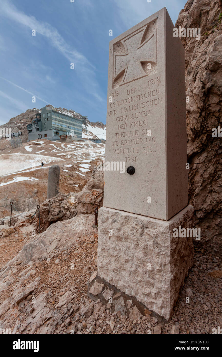 Column obelisk in memory of the fallen of World War I posed at the beginning of the walkways of Punta Serauta, the background, the cable car station, Marmolada, Dolomites Stock Photo