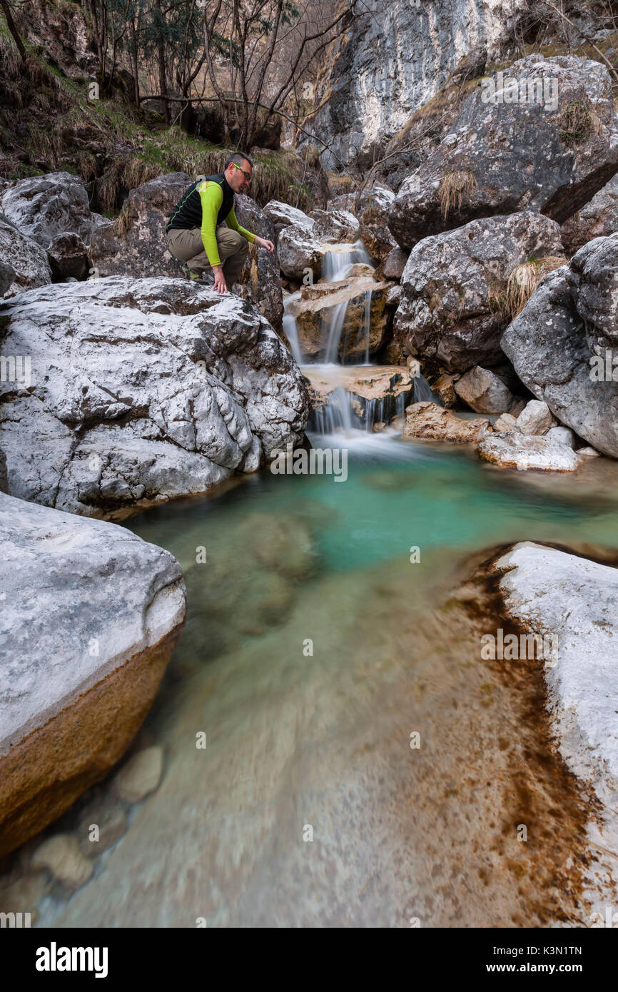 Hiker looking at the small waterfalls of turquoise water in val Salet, Monti del Sole, National park Belluno Dolomites, Italy Stock Photo