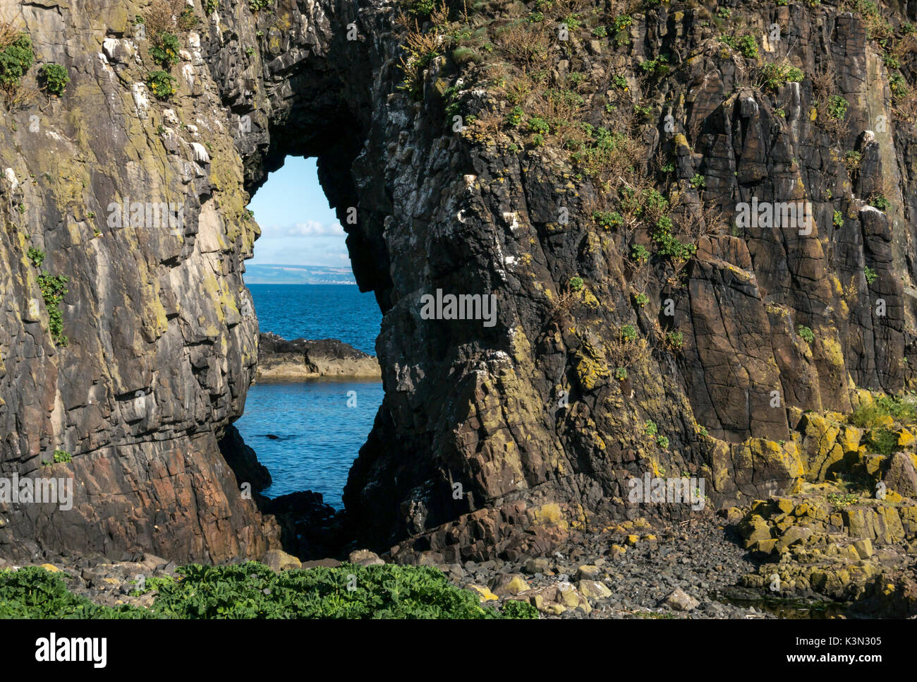 Looking through a natural sea worn arch purported to look like a lady in a veil, Fidra Island, Firth of Forth Scotland UK on a sunny day with blue sky Stock Photo