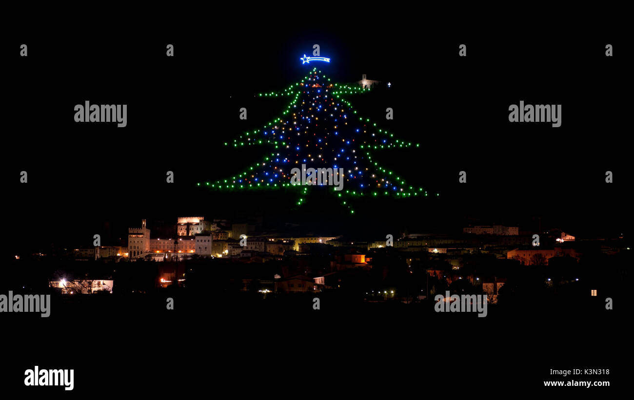 The biggest Christman tree of the world, drawn with colored lights on the Ingino mountain behind the town of Gubbio, Umbria, Italy Stock Photo