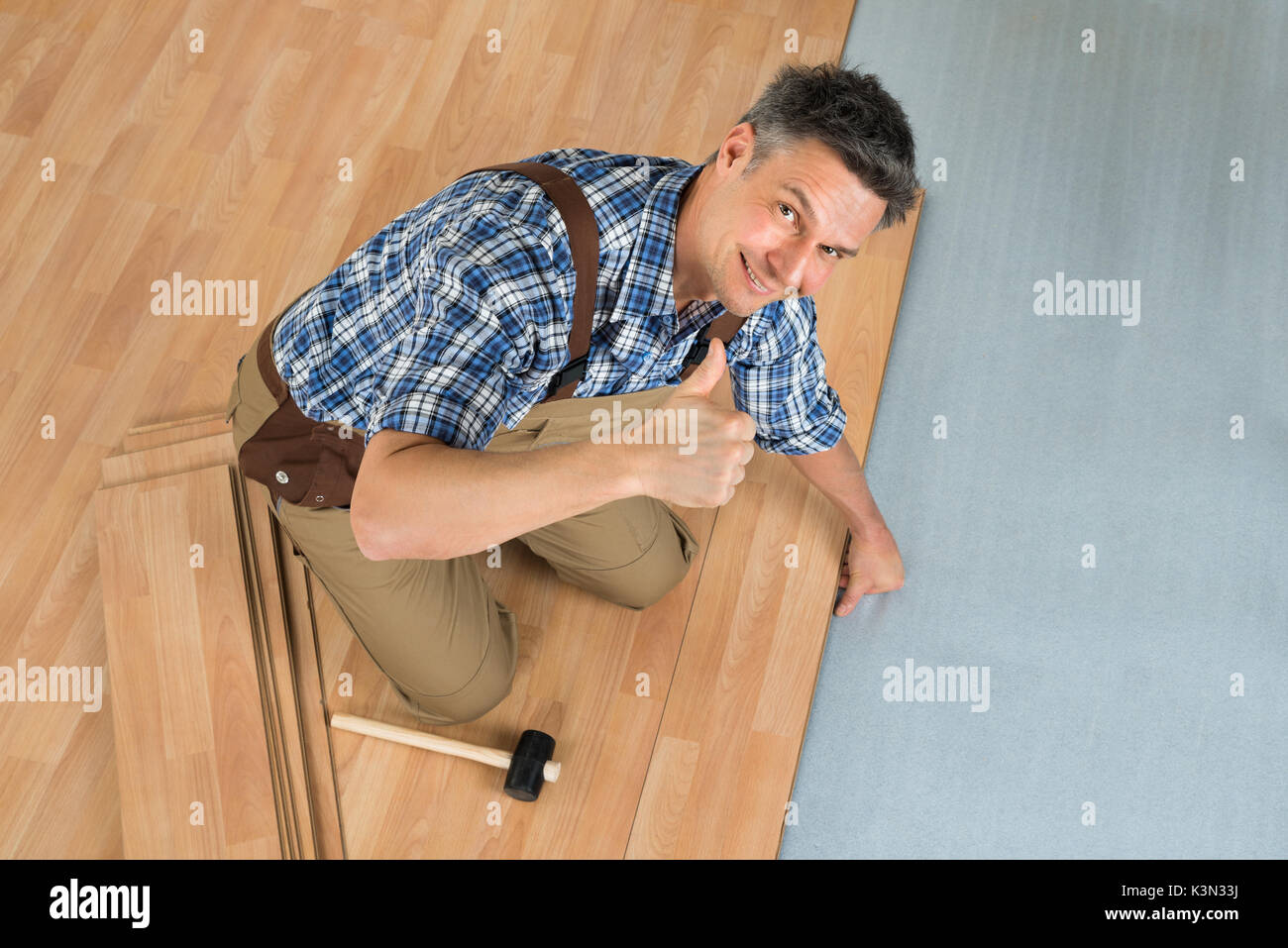 High Angle View Of A Smiling Worker Assembling New Laminate Floor Stock Photo