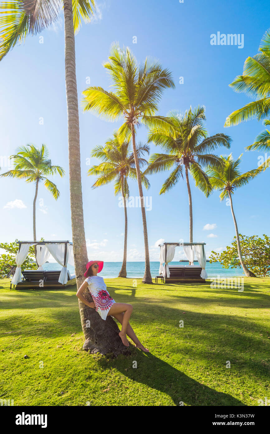 Playa Moron, Las Terrenas, Samana Peninsula, Dominican Republic. Woman relaxing on a palm-fringed meadow (MR). Stock Photo